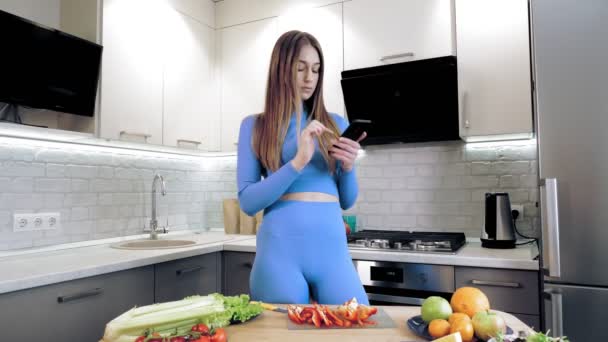 Femme cuisine des aliments sains, salade de légumes crus à la cuisine moderne. Elle cherche une recette en ligne, à l'aide d'un smartphone, applications de livres de cuisine mobiles. Alimentation saine, écoalimentaire — Video