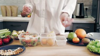 İnternette yemek yapmak. Sağlıklı yemek. Yemek konteynırları. Kadın öğle yemeğini tekrar kullanılabilir yemek kutularında ve beslenme çantalarında paketliyor. Plastik konteynırlarda ev yapımı yemek. Kargo Servisi