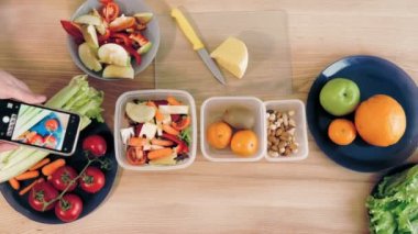 İnternette yemek yapmak. Sağlıklı yemek. Yakın plan. Üst Manzara. Kadın blogcu, sosyal medya için akıllı telefondan ev mutfağında vejetaryen yemeğinin fotoğraflarını ve videosunu çekiyor. Mutfak vlogları, sosyal ağlar.