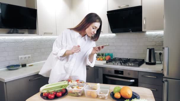 Cocinar en línea. comida saludable. Blogger mujer tomando fotos y video de almuerzo vegetariano en el teléfono inteligente para las redes sociales, en la cocina casera. vlogging culinario, redes sociales. — Vídeos de Stock