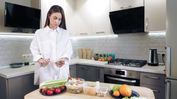 Cocinar en línea. comida saludable. Blogger mujer tomando fotos y video de almuerzo vegetariano en el teléfono inteligente para las redes sociales, en la cocina casera. vlogging culinario, redes sociales. — Vídeos de Stock