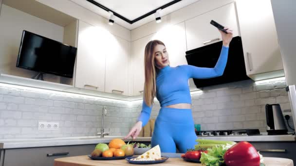 Приготовление пищи онлайн. здоровую пищу. Женщина-блогер делает селфи, снимает видео о вегетарианском обеде на смартфоне для социальных сетей, на домашней кухне. кулинарные блоги, социальные сети. — стоковое видео