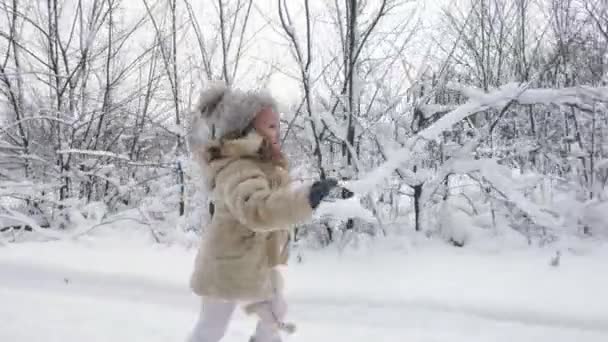 Zimní rodinná aktivita venku. boční pohled. Šťastná holčička běží hustým sněhem na cestě ke své matce, během sněžení. rodina se baví, tráví spolu čas na sněžném zimním dni — Stock video