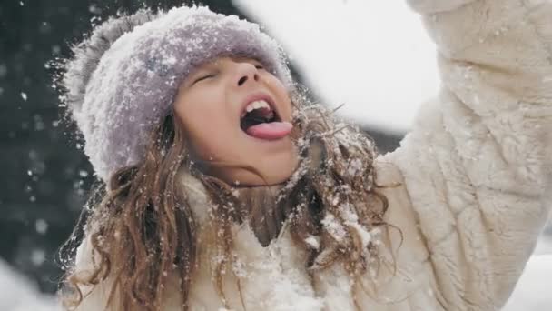 Divertimento da família do inverno. pegar flocos de neve com língua. Feliz gracinha, linda menina está pegando flocos de neve com a língua, desfrutando de neve e queda de neve, se divertindo no dia de inverno nevado. câmara lenta. — Vídeo de Stock