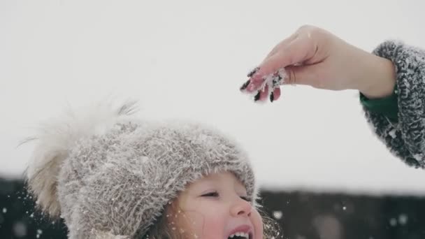 Χειμωνιάτικη οικογενειακή διασκέδαση. πιάσει νιφάδες χιονιού με τη γλώσσα. Ευτυχισμένο χαριτωμένο, όμορφο κοριτσάκι πιάνει νιφάδες χιονιού με τη γλώσσα της, απολαμβάνοντας το χιόνι και τις χιονοπτώσεις, διασκεδάζοντας την χιονισμένη χειμωνιάτικη μέρα. αργή κίνηση. — Αρχείο Βίντεο
