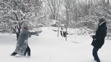 Karlı kış eğlencesi. Kartopu atmak. Mutlu çift, kadın ve erkek kartopu oynuyorlar, dışarıda eğleniyorlar, karlı kış günlerinde birlikte vakit geçiriyorlar. yavaş çekim