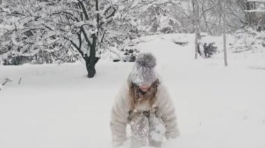 Karlı kış eğlencesi. Sıcak kış kıyafetleri içinde mutlu, sevimli, güzel bir kız, kar yağarken, kar yağarken, dışarıda eğlenirken, karlı kış günlerinde, parkta ya da ormanda..