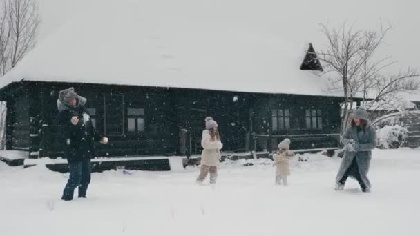 Zimowa rodzinna zabawa. rzucanie śnieżkami. Szczęśliwa 4-osobowa rodzina bawi się śniegiem i raduje się opadami śniegu, bawi się na świeżym powietrzu, spędza czas razem w śnieżny zimowy dzień. zwolniony ruch — Wideo stockowe