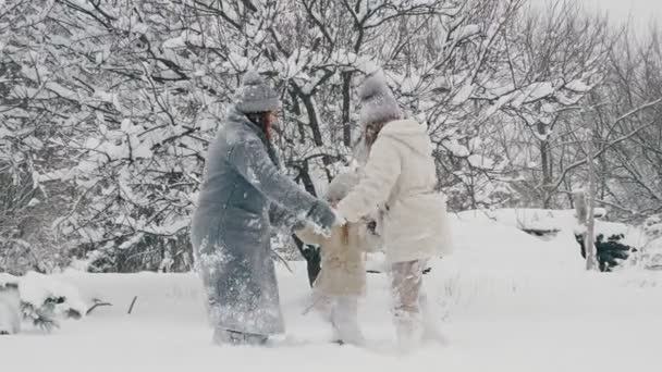 Winter family fun. Happy family is enjoying of snow and snowfall, having fun outdoors, spending time together on snowy winter day in park or forest. slow motion — Stock Video