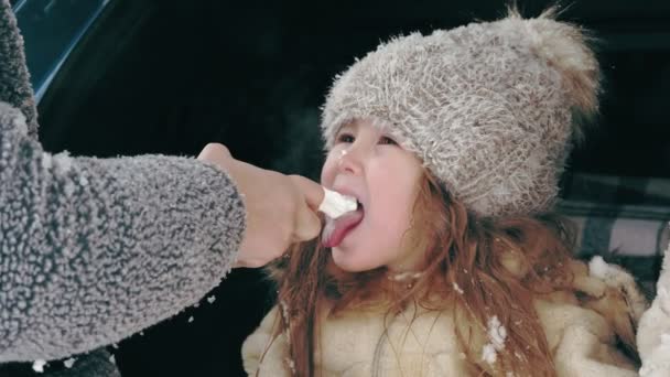 冬のお茶ピクニック屋外。幸せな子供はスプレー、チューブからホイップクリームを食べています。雪の冬の日、雪の日、. — ストック動画