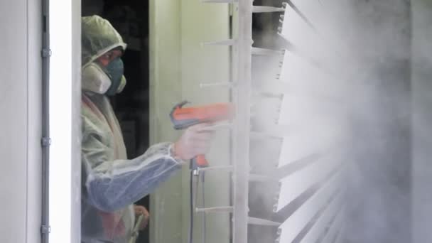 그림을 그리고 있다. 산업화 된 그림. 보호용 양복과 마스크를 쓰는 근로자는 페인트 작업장에서 스프레이 총으로부터 금속 제품에 흰색 분말 코트를 착용 한다. 산업화 된 그림 — 비디오