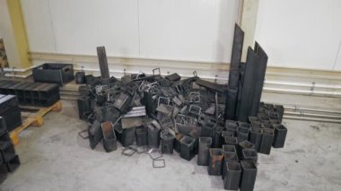 Metal kesme boruları, borular ve çubuklar metal atölyesinin zemininde ya da depoda rastgele yatıyor. Metal boruların lazer kesimi..