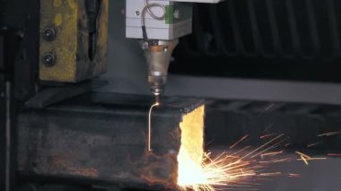 Metal borular için lazer kesme makinesi. Yakın plan. Yan görünüş. CNC fiber lazerli modern makine kare metal boruları kesiyor. Kesme işlemi sırasında lazer ışınından parlak kıvılcımlar uçuşuyor