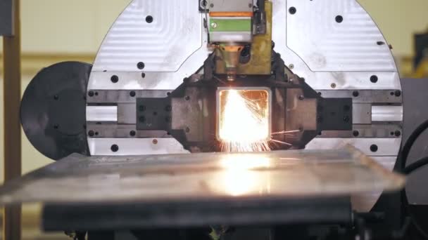 Machine de découpe laser pour tuyaux métalliques. Gros plan. machine moderne avec laser à fibre CNC coupe tuyau carré en métal. étincelles brillantes volent du faisceau laser pendant le processus de coupe — Video