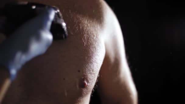 Haarverwijdering. Harig. close-up. Hand in hand knipt mannelijke borsthaar met een elektrische tondeuse, machine. procedure van mannelijk haar knippen in de schemering, in lichtstralen. Lichaamsverzorging. — Stockvideo