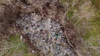 Ormandaki çöplük. Ekolojik bir sorun. Bahar ormanının ortasında yasadışı çöplük. Havadan görünüşlü. Bir yığın plastik torba, yiyecek atıkları, çöpler, açık havaya atılmış. Çevre kirliliği