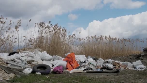 Basurero cerca del río. Problema ecológico. Vertido ilegal de residuos de construcción en la orilla del río. Una pila de basura, basura, tirada al aire libre. Vertedero. contaminación ambiental. — Vídeos de Stock