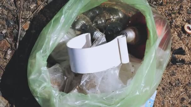 Vuilnis buiten. close-up. vrijwilliger, in beschermende handschoenen, is het oprapen van gebroken oude gebruikte glazen bollen en andere rommel, afval buiten gegooid, en zet het in plastic vuilniszak. afval — Stockvideo