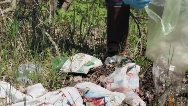 Basura al aire libre. Primer plano. voluntario, en guantes de protección, está recogiendo plástico y otras basuras, basura tirada al aire libre, y ponerlo en la bolsa de basura de plástico. basura al aire libre. Ecológico — Vídeos de Stock