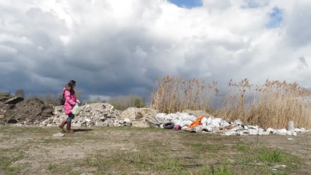 Śmieci na zewnątrz. wysypisko śmieci w pobliżu rzeki. kobieta, wolontariuszka, z plastikowym workiem na śmieci przechadza się po nielegalnym wysypisku odpadów budowlanych na brzegu rzeki, stosy śmieci, śmieci, wyrzucone na zewnątrz — Wideo stockowe