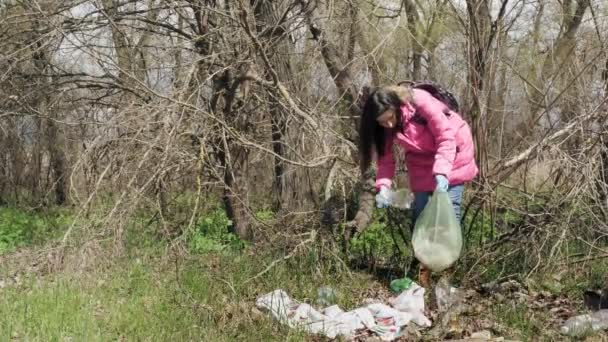 Trash outdoors. garbage outdoors. volunteer, in protective gloves, is picking up plastic and other rubbish, trash thrown outdoors, and putting it into plastic garbage bag. rubbish outdoors. Ecological — Stock Video