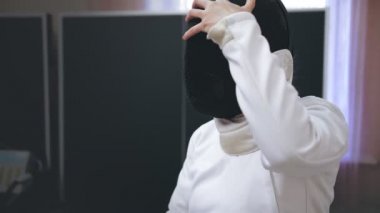 Engelli atlet. Eskrim. Felç oyunları. Tekerlekli sandalye çiti. Beyaz eskrim üniformalı engelli kadın eskrimci portresi antrenmandan önce siyah eskrim kaskı takıyor. Kadın sporcu