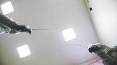 Eskrim. Alt-üst görüntü. Eller ve kılıçlar. Eskrim. Yüzlerinde eskrim kasklarıyla idmanda Rapier 'ları ve idmanları tutuyorlardı. Engelli sporcu.