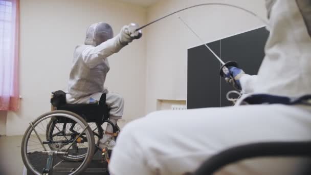 Atleta discapacitado. Esgrima. combate en duelo de esgrima de dos atletas de esgrima en silla de ruedas con habilidades físicas reducidas. Practican la técnica de duelo durante el entrenamiento. — Vídeo de stock