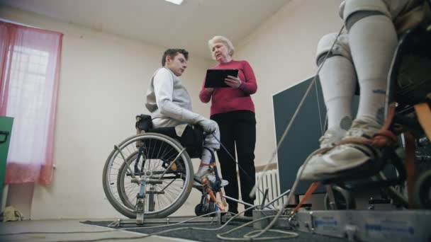 Idrottsman med funktionshinder. Fäktning. träning av rullstolsburna idrottare med nedsatt fysisk förmåga. Kvinnlig tränare visar kampen duell teknik på digital surfplatta. — Stockvideo