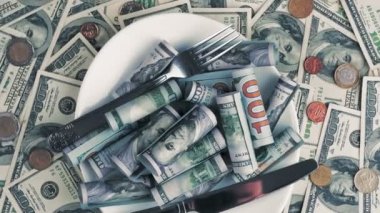 Para için. Dolar banknotları ve bozuk paralar. Yakın plan. Döndürme. 100 dolarlık banknotlar ve farklı madeni paralar. Bir yığın dolarlar, çatal bıçak ve çatal bıçak dolu bir tabak.