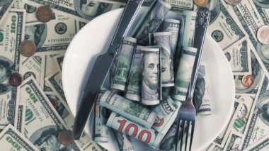 Para için. Dolar banknotları ve bozuk paralar. Yakın plan. Döndürme. 100 dolarlık banknotlar ve farklı madeni paralar. Bir yığın dolarlar, çatal bıçak ve çatal bıçak dolu bir tabak.