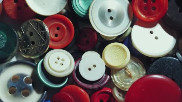 縫いボタン。接近中だ。回転だ。様々な丸みを帯びた色の縫製ボタンがターンテーブル上で回転。ループ動作の背景。色、ファッション、ドレッシング、縫製、テーラーメイドの概念. — ストック動画