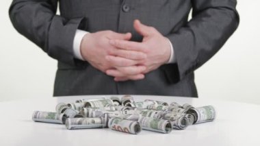 İş adamı ve para, nakit. Yakın plan. Birçok yuvarlanan yüz dolarlık banknotlar beyaz pikapta dönüyor. İş adamı, resmi bir iş elbisesi içinde.