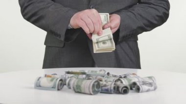 İş adamı ve para, nakit. Yakın plan. İş adamı, resmi takım elbiseli, elinde 100 dolarlık banknotlar tutuyor. Beyaz arka plan. Yatırım, başarı, finansal beklentiler veya kariyer