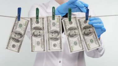 Para, para, iş. Yakın plan. Beyaz bluzlu kadın, ipteki mandallarla yüz dolarlık banknotları açıyor. Tasarruf ve mevduat. Kara para aklama, açık deniz. Rüşvet, yolsuzluk konsepti. Finans