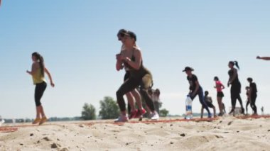 Grup sporu dışarıda yapılıyor. Bulanık odak. Aktif giysi giyen insanlar spor sahasında, plajda birlikte egzersiz yapıyorlar. Yan görünüş. sağlıklı yaşam tarzı konsepti. Spor salonu açık havada. spor