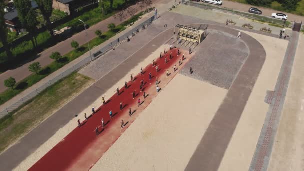 Entrenamiento de fitness en grupo al aire libre. fitness al aire libre. Vista aérea. Gran grupo de personas, con ropa deportiva, está haciendo ejercicio en el campo de deportes, en la playa, al aire libre. concepto de estilo de vida saludable. deporte — Vídeos de Stock