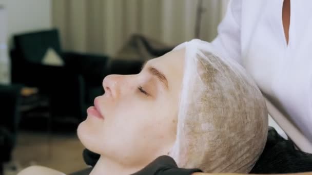 Procedure cosmetiche per le donne. cosmetologia. preparazione a procedura cosmetica. primo piano. estetista mette un cappello usa e getta su una testa delle donne, nascondendo i capelli, prima di iniziare la procedura cosmetica. a — Video Stock