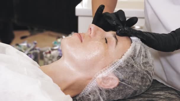 Terapia de belleza. masaje facial. Cosmetología cuidado de la piel. Primer plano. mujer está recibiendo procedimiento de lavado facial cosmético, tonied y piel limpia, en la clínica de belleza. antienvejecimiento. rejuvenecimiento facial. — Vídeos de Stock