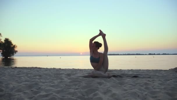 Se estendendo ao ar livre. silhueta de ioga. praia de ioga. Atlético jovem está praticando ioga na praia durante o pôr do sol ou nascer do sol. Treinamento de fitness ao ar livre. a praticar desporto de manhã. Fitness, desporto — Vídeo de Stock