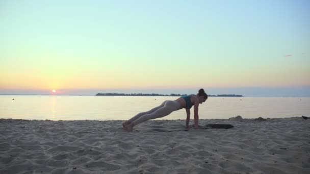 Estiramiento al aire libre. silueta de yoga. Playa de yoga. La joven atlética está practicando yoga en la playa al atardecer o al amanecer. Entrenamiento físico al aire libre. haciendo deporte por la mañana. Fitness, deporte — Vídeos de Stock