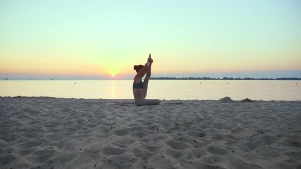 Estiramiento al aire libre. silueta de yoga. Playa de yoga. La joven atlética está practicando yoga en la playa al atardecer o al amanecer. Entrenamiento físico al aire libre. haciendo deporte por la mañana. Fitness, deporte — Vídeo de stock