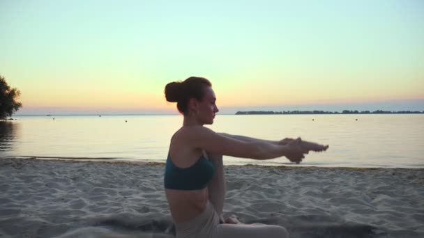 야외에 뻗어 있다. 요가 실루엣. 요가 해변. 운동 선수인 젊은 여자는 해 가질 때나 일출 때 해변에서 요가를 연습 한다. 야외에서의 건강 훈련. 아침에 운동하는 거. 건강, 운동 — 비디오