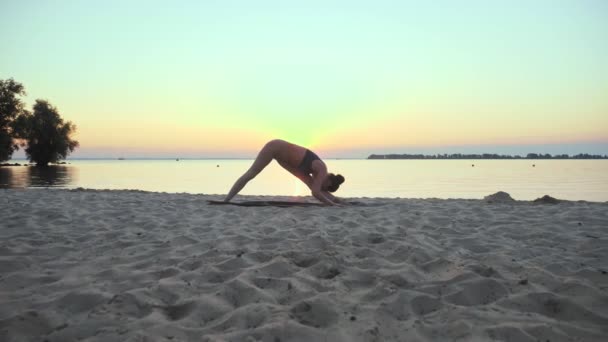 Se estendendo ao ar livre. silhueta de ioga. praia de ioga. Atlético jovem está praticando ioga na praia durante o pôr do sol ou nascer do sol. Treinamento de fitness ao ar livre. a praticar desporto de manhã. Fitness, desporto — Vídeo de Stock
