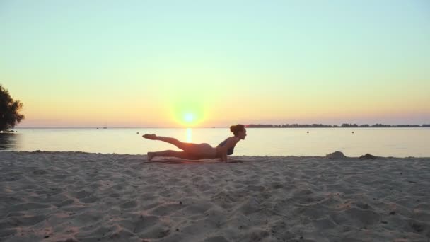 Se estendendo ao ar livre. silhueta de ioga. praia de ioga. Atlético jovem está praticando ioga na praia durante o pôr do sol ou nascer do sol. Treinamento de fitness ao ar livre. a praticar desporto de manhã. Fitness, desporto — Vídeo de Stock