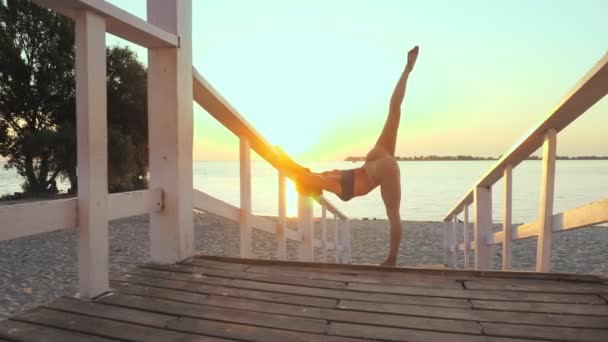 Barre. se estendendo ao ar livre. praia de ioga. Treino de ballet. Jovem atlética está fazendo exercícios na praia durante o pôr do sol ou nascer do sol. Treinamento de fitness ao ar livre. Fitness, balé, esporte, ioga e — Vídeo de Stock