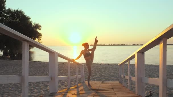 Barre. Açık havada uzanıyor. Yoga kumsalı. Bale antrenmanı. Atletik genç kadın gün batımında ya da gün doğumunda plajda egzersiz yapıyor. Spor salonu açık havada. Fitness, bale, spor, yoga ve — Stok video