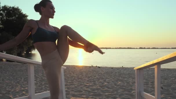 Barre. stretching outdoors. yoga beach. ballet workout. Athletic young woman is doing exercises at the beach during sunset or sunrise. Fitness training outdoors. Fitness, ballet, sport, yoga and — Stock Video