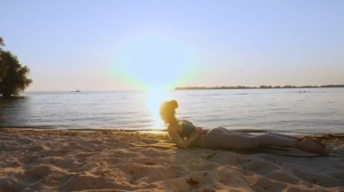 Bar antrenmanı. Açık havada uzanıyor. Yoga kumsalı. Atletik genç kadın gün batımında ya da gün doğumunda plajda minder üzerinde egzersiz yapıyor. Spor salonu açık havada. Fitness, bale, spor, yoga ve