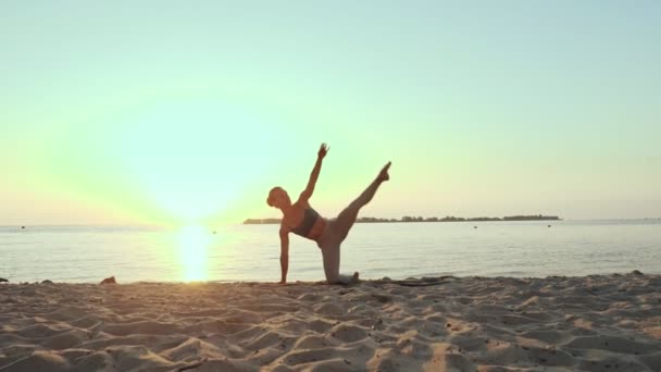 Bar antrenmanı. Açık havada uzanıyor. Yoga kumsalı. Atletik genç kadın gün batımında ya da gün doğumunda plajda minder üzerinde egzersiz yapıyor. Spor salonu açık havada. Fitness, bale, spor, yoga ve — Stok video